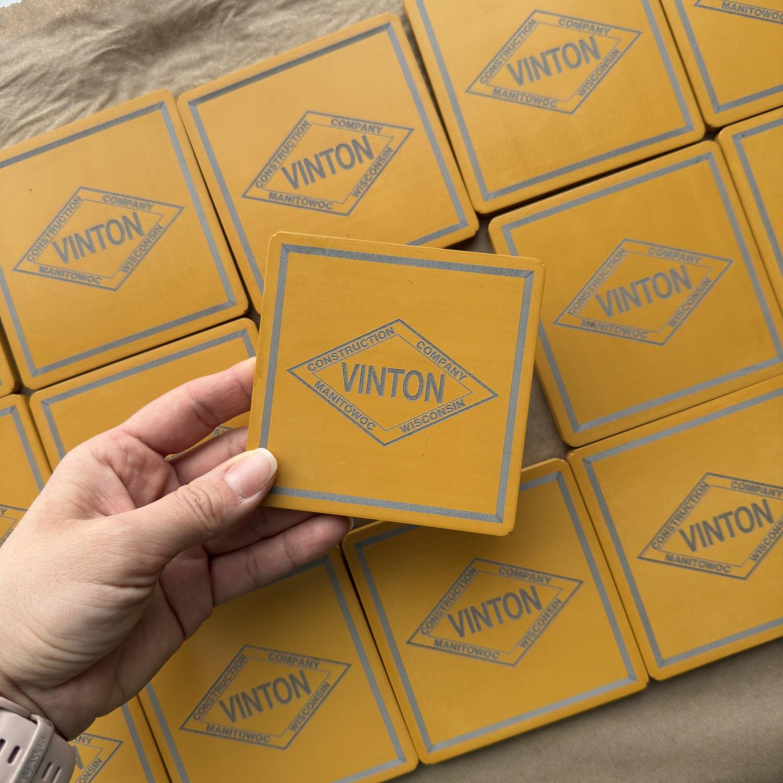 Square custom concrete coasters in construction yellow with an engraved logo