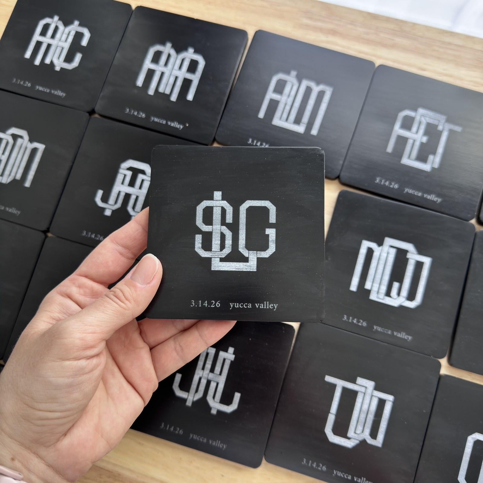 Black concrete wedding coasters, each engraved with a different guest monogram