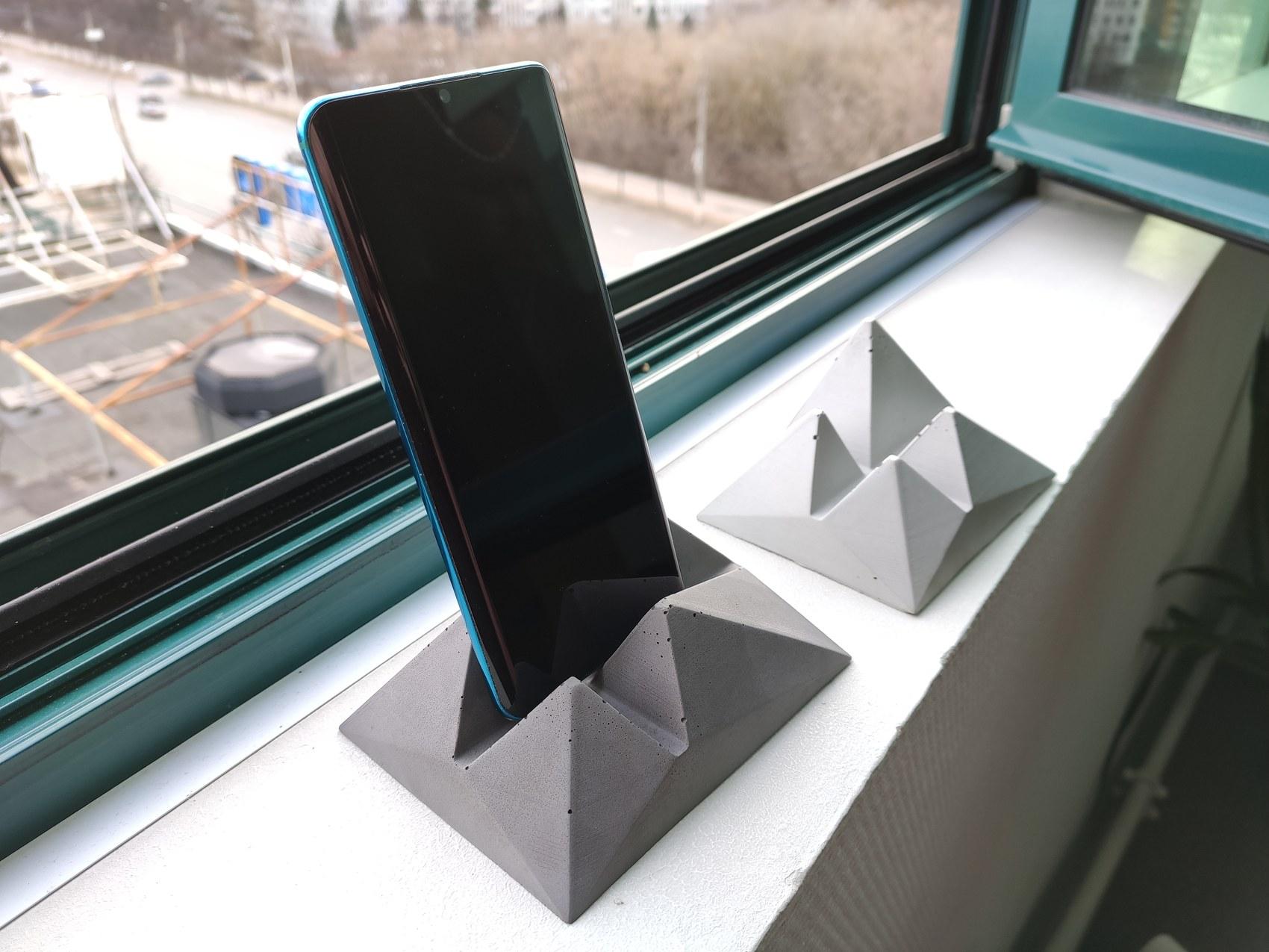Grey concrete phone stand holding a phone upright
