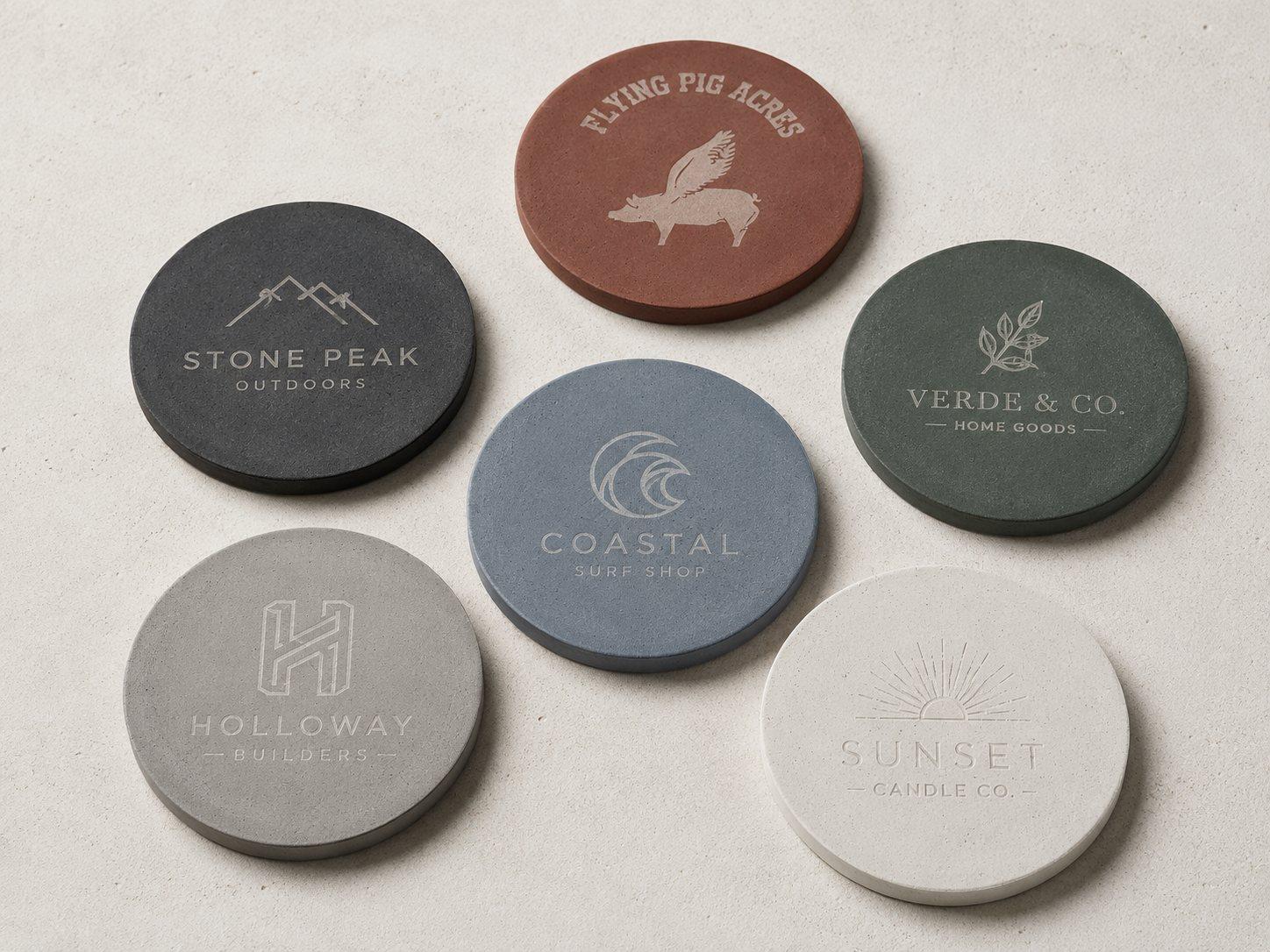 Round concrete coasters in six colors, each laser engraved with a different client logo
